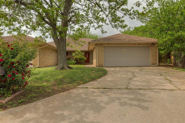 single story home with a front lawn, brick siding, driveway, and an attached garage