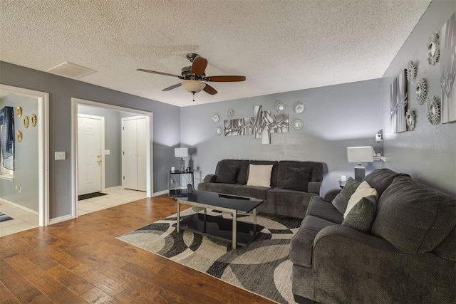 living area with light wood-style floors, visible vents, ceiling fan, and a textured ceiling