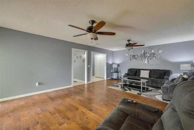 living room featuring a textured ceiling, baseboards, a ceiling fan, and wood finished floors
