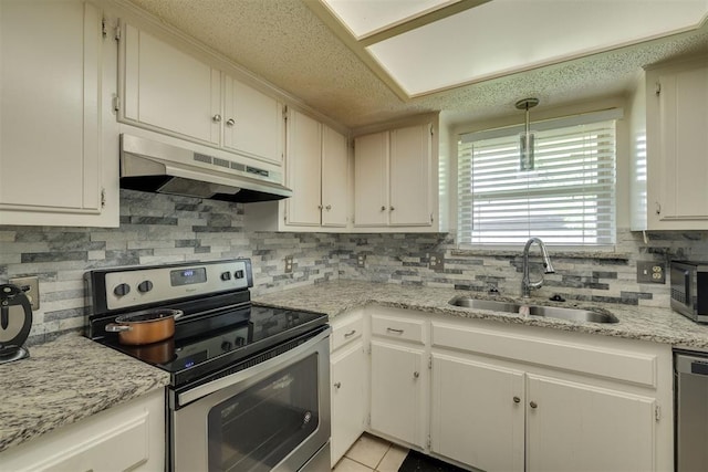 kitchen with hanging light fixtures, a sink, under cabinet range hood, appliances with stainless steel finishes, and decorative backsplash