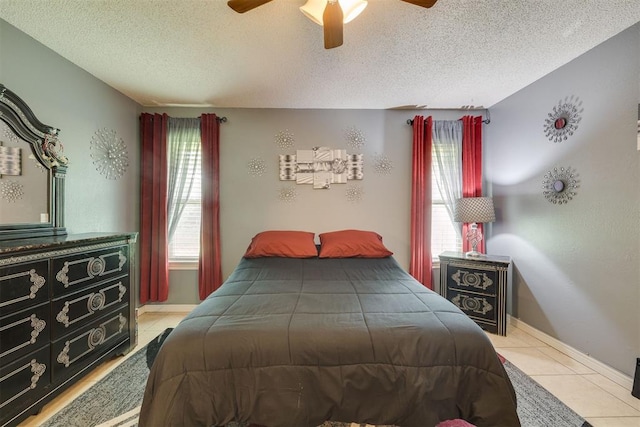bedroom featuring baseboards, tile patterned flooring, ceiling fan, and a textured ceiling
