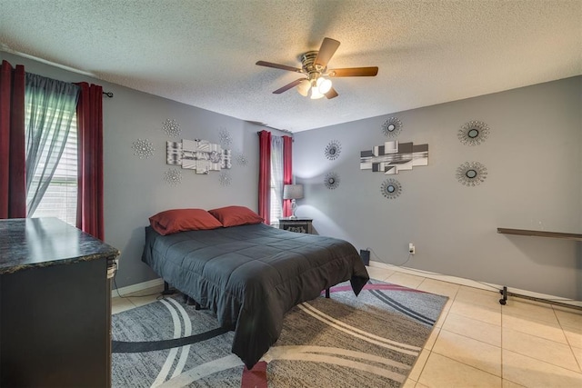 bedroom featuring a textured ceiling, light tile patterned floors, a ceiling fan, and baseboards