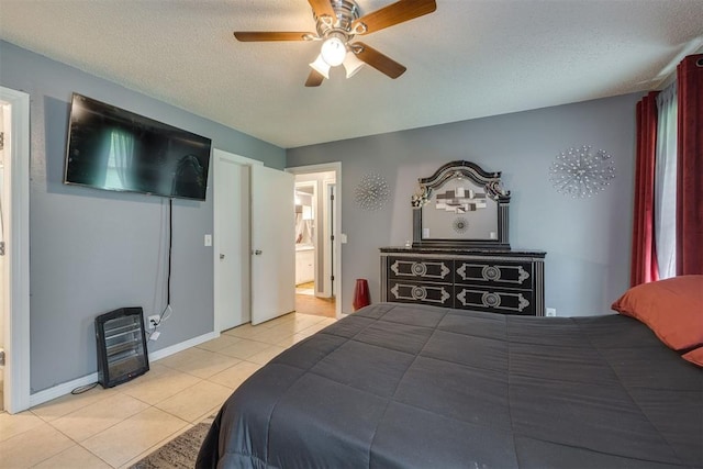 tiled bedroom featuring a textured ceiling, connected bathroom, baseboards, and a ceiling fan