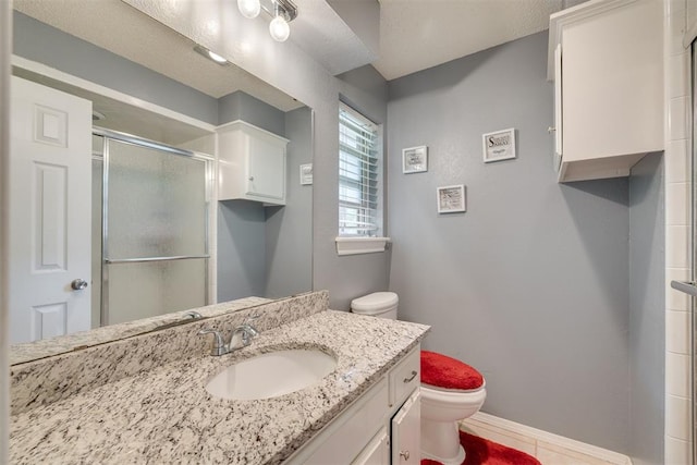 bathroom featuring a stall shower, baseboards, toilet, vanity, and tile patterned flooring