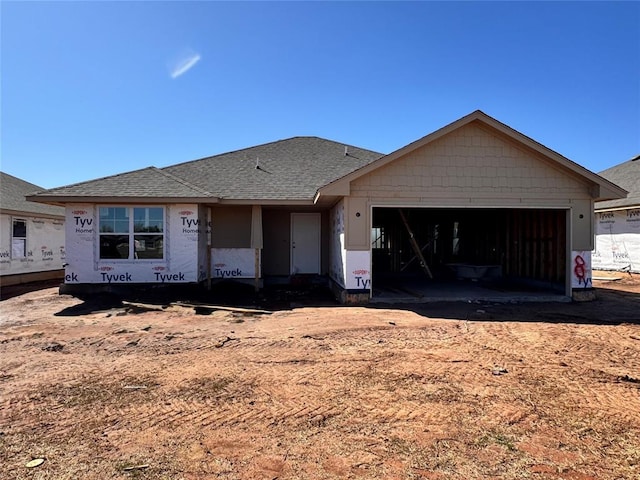 unfinished property with an attached garage and a shingled roof