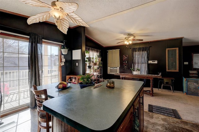 kitchen featuring carpet floors, lofted ceiling, visible vents, ceiling fan, and a textured ceiling