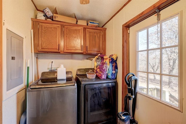 laundry area featuring crown molding, washing machine and clothes dryer, cabinet space, a textured ceiling, and electric panel