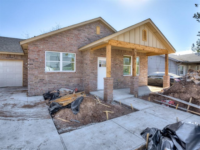 ranch-style home featuring a garage, roof with shingles, brick siding, and board and batten siding