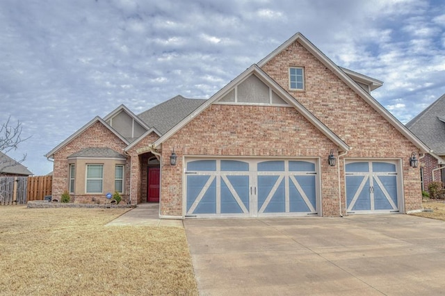 craftsman-style house featuring driveway, a garage, fence, and brick siding