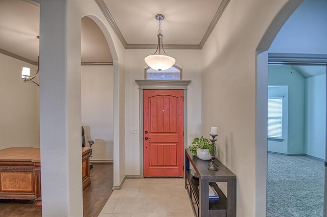 entryway featuring baseboards, arched walkways, and crown molding