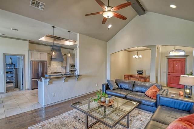 living area featuring light wood-style flooring, visible vents, arched walkways, and beamed ceiling