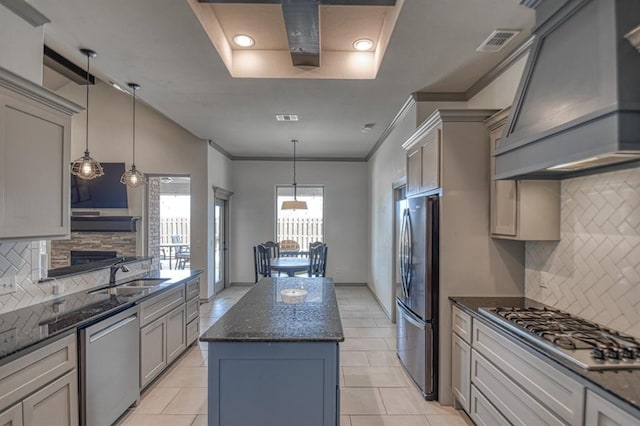 kitchen featuring a center island, stainless steel appliances, visible vents, a sink, and premium range hood