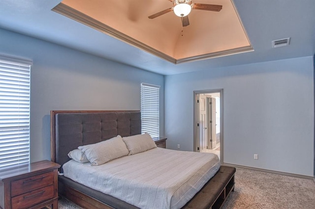 bedroom featuring carpet, a raised ceiling, visible vents, ensuite bath, and baseboards