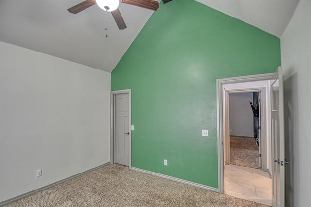 unfurnished bedroom featuring baseboards, high vaulted ceiling, a ceiling fan, and light colored carpet