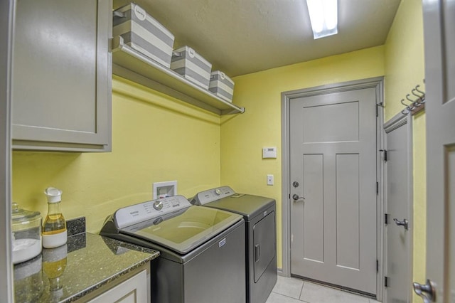 laundry area featuring light tile patterned floors, cabinet space, and separate washer and dryer