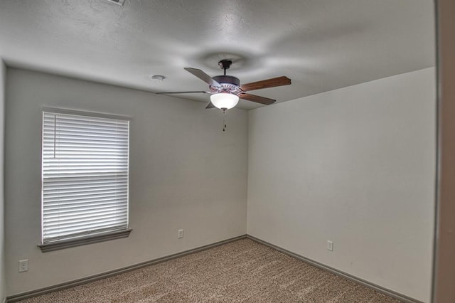 spare room featuring carpet, baseboards, and a ceiling fan