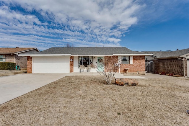 single story home with driveway, brick siding, and an attached garage