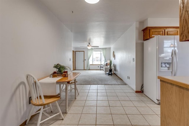 kitchen featuring light tile patterned floors, brown cabinetry, ceiling fan, light countertops, and white fridge with ice dispenser