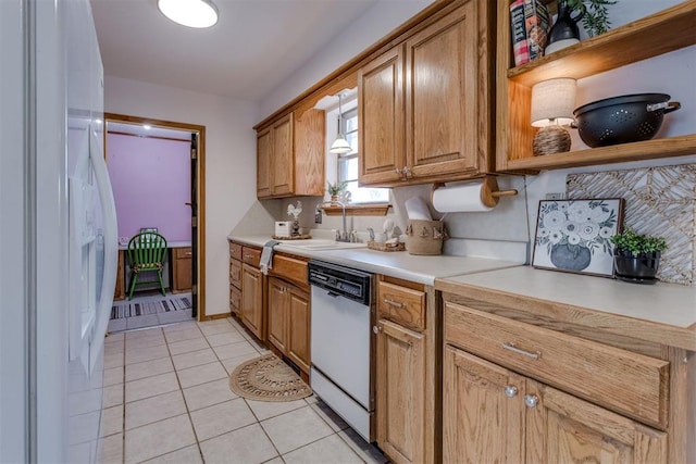 kitchen with light tile patterned floors, tasteful backsplash, light countertops, a sink, and white appliances