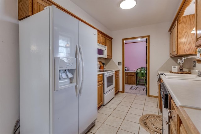 kitchen featuring brown cabinets, white appliances, light countertops, and light tile patterned floors