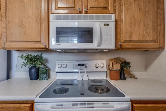 kitchen with light countertops, white appliances, and brown cabinets