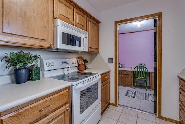 kitchen featuring light tile patterned floors, light countertops, white appliances, and brown cabinetry