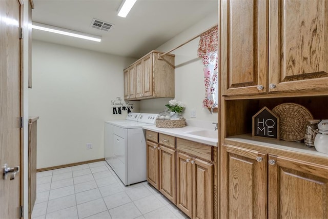 washroom featuring cabinet space, visible vents, washing machine and dryer, a sink, and light tile patterned flooring