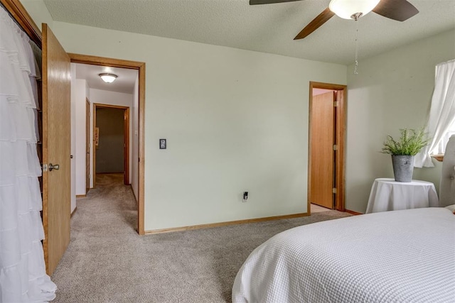 bedroom featuring baseboards, ceiling fan, a textured ceiling, and light colored carpet