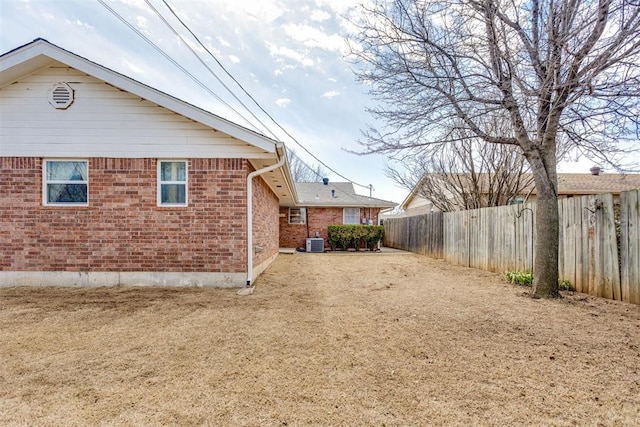 exterior space with central air condition unit, fence, and brick siding