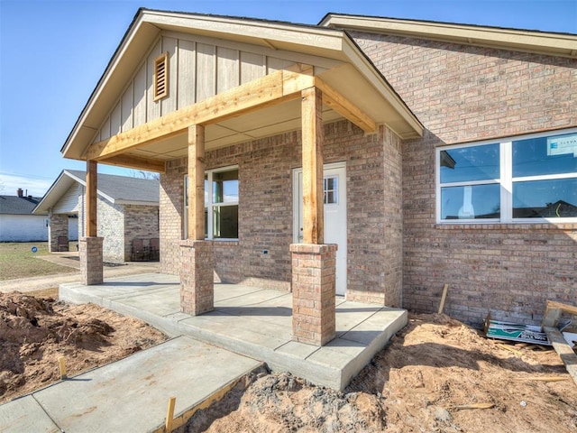 doorway to property featuring board and batten siding and brick siding