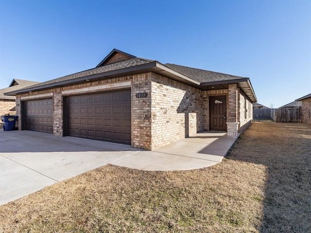 view of front of home featuring brick siding, fence, driveway, and an attached garage