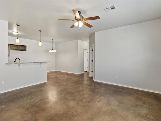 unfurnished living room with concrete flooring, ceiling fan with notable chandelier, visible vents, and baseboards