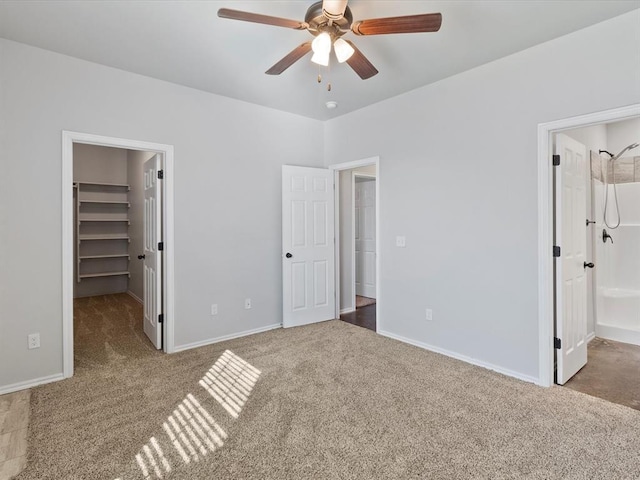 unfurnished bedroom featuring baseboards, connected bathroom, a walk in closet, carpet flooring, and a closet