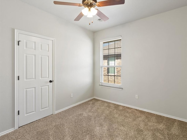 carpeted spare room featuring ceiling fan, visible vents, and baseboards