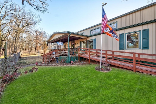 back of property with a yard, a wooden deck, and fence