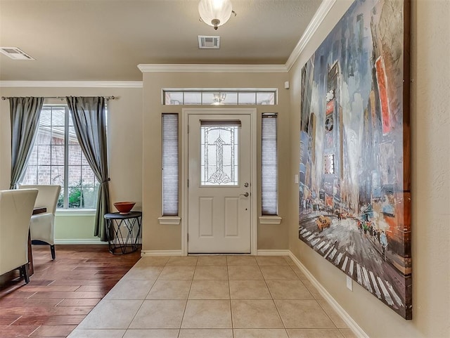 foyer with visible vents, crown molding, and baseboards