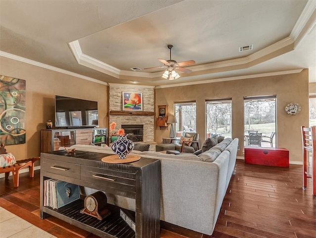 living area featuring a fireplace, wood finished floors, visible vents, plenty of natural light, and a raised ceiling