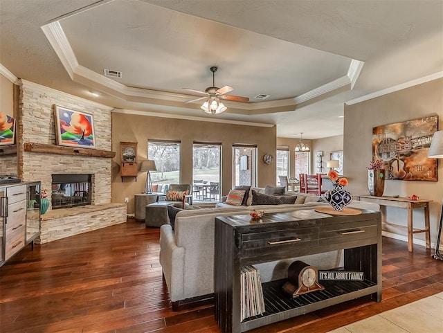 living room featuring visible vents, a fireplace, a tray ceiling, and hardwood / wood-style floors