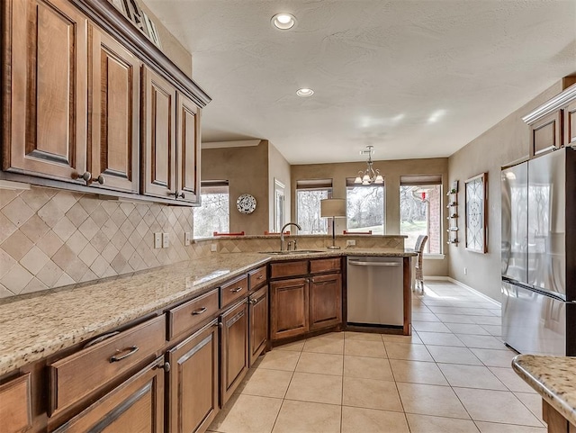 kitchen with light tile patterned floors, stainless steel appliances, a peninsula, a sink, and decorative backsplash