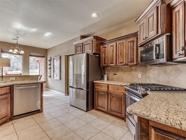 kitchen with light stone countertops, light tile patterned floors, appliances with stainless steel finishes, and decorative backsplash