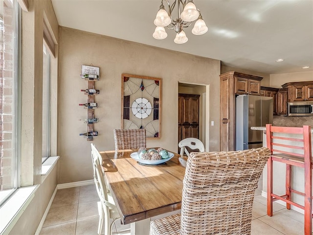 dining space with light tile patterned floors, a chandelier, and baseboards