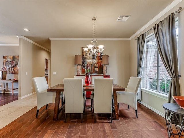 dining space featuring an inviting chandelier, baseboards, visible vents, and wood finished floors