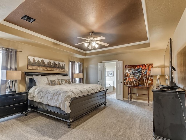 bedroom with a textured ceiling, a tray ceiling, and carpet