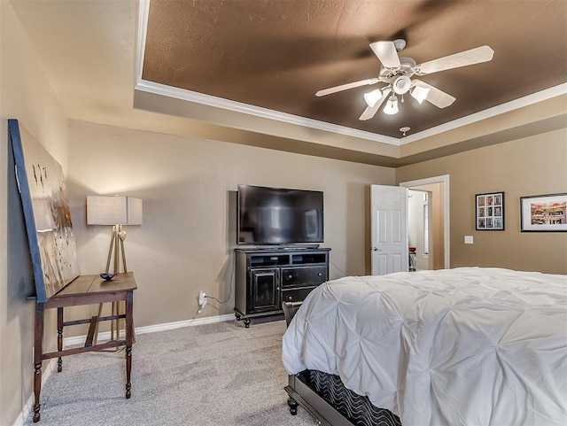 bedroom featuring carpet floors, a tray ceiling, ornamental molding, ceiling fan, and baseboards