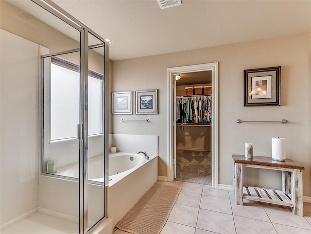 bathroom featuring a stall shower, a walk in closet, tile patterned floors, and a bath