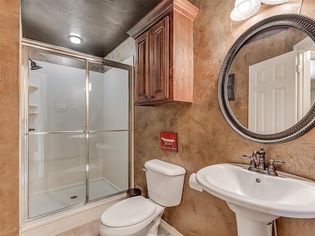 bathroom featuring a stall shower, a sink, and toilet