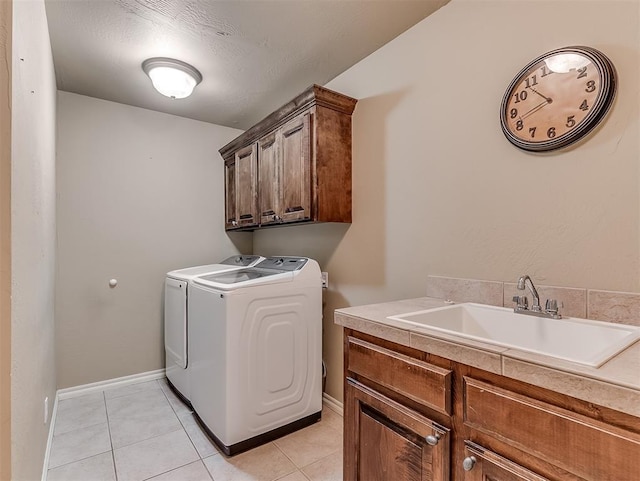 clothes washing area with light tile patterned floors, a sink, baseboards, cabinet space, and washer and clothes dryer