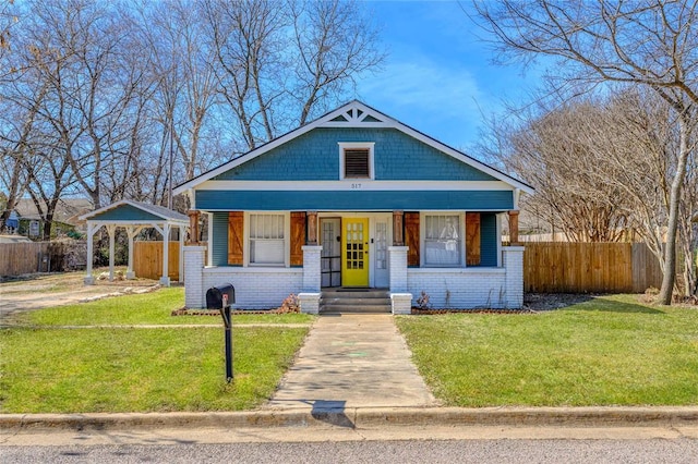 bungalow-style home with brick siding, covered porch, a gazebo, fence, and a front lawn