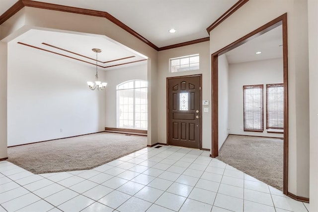 entryway featuring crown molding, light tile patterned floors, an inviting chandelier, and light colored carpet