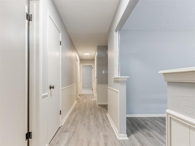 hallway featuring baseboards and light wood-style floors